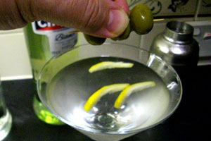 Twist the lemon rind and squeeze a couple of drops of olive juice in.